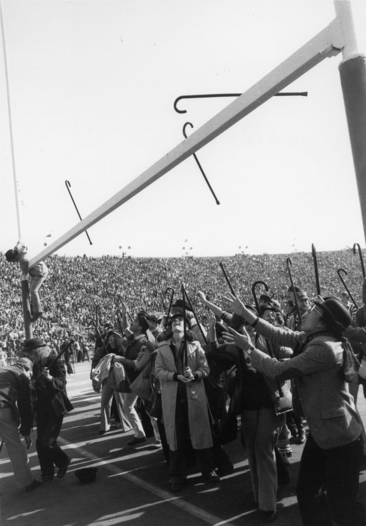 Student climbs goal post during the Cane Toss.