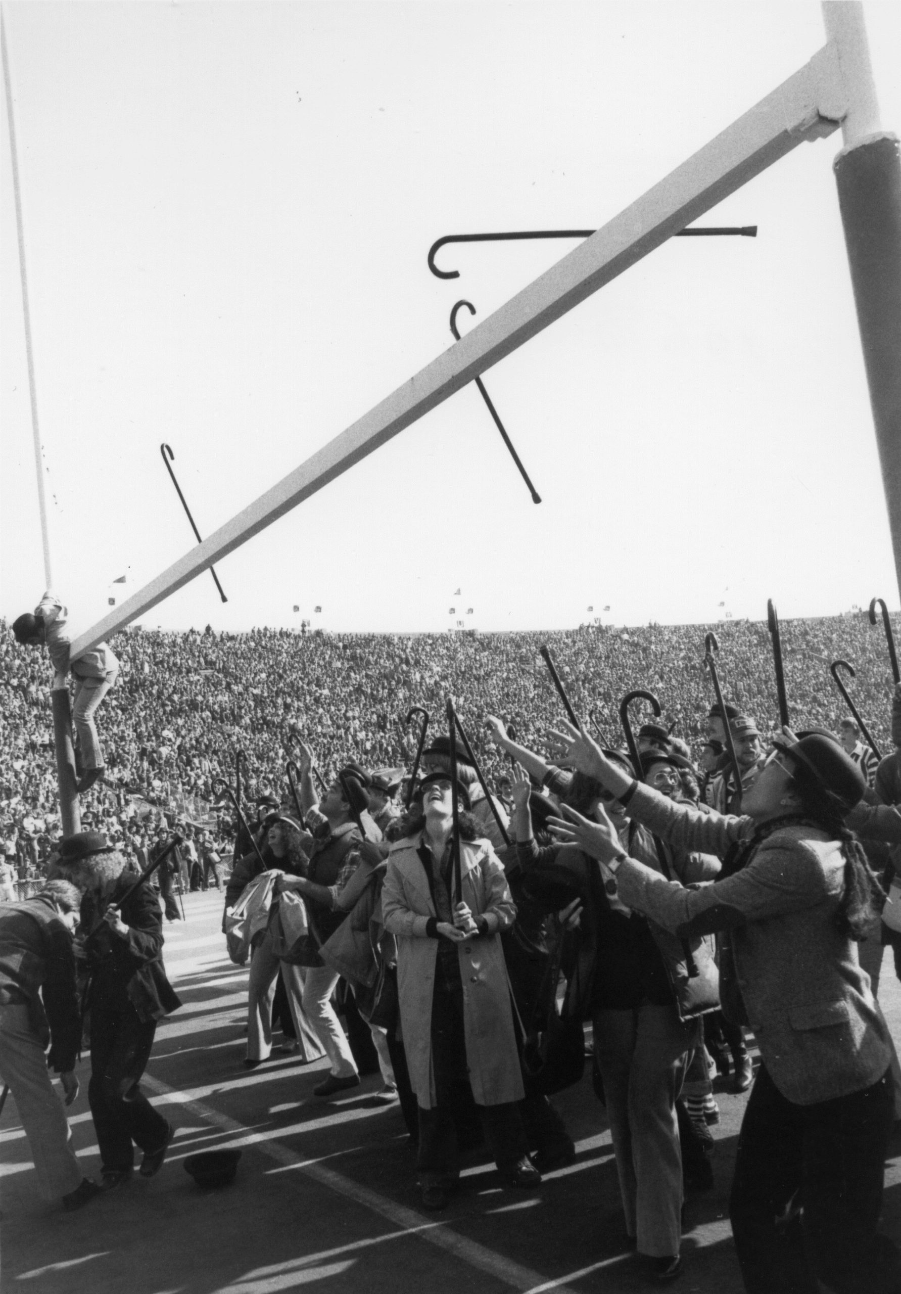 Student climbs goal post during the Cane Toss.