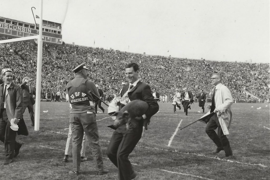 Student participates in the Cane Toss while holding a pig.